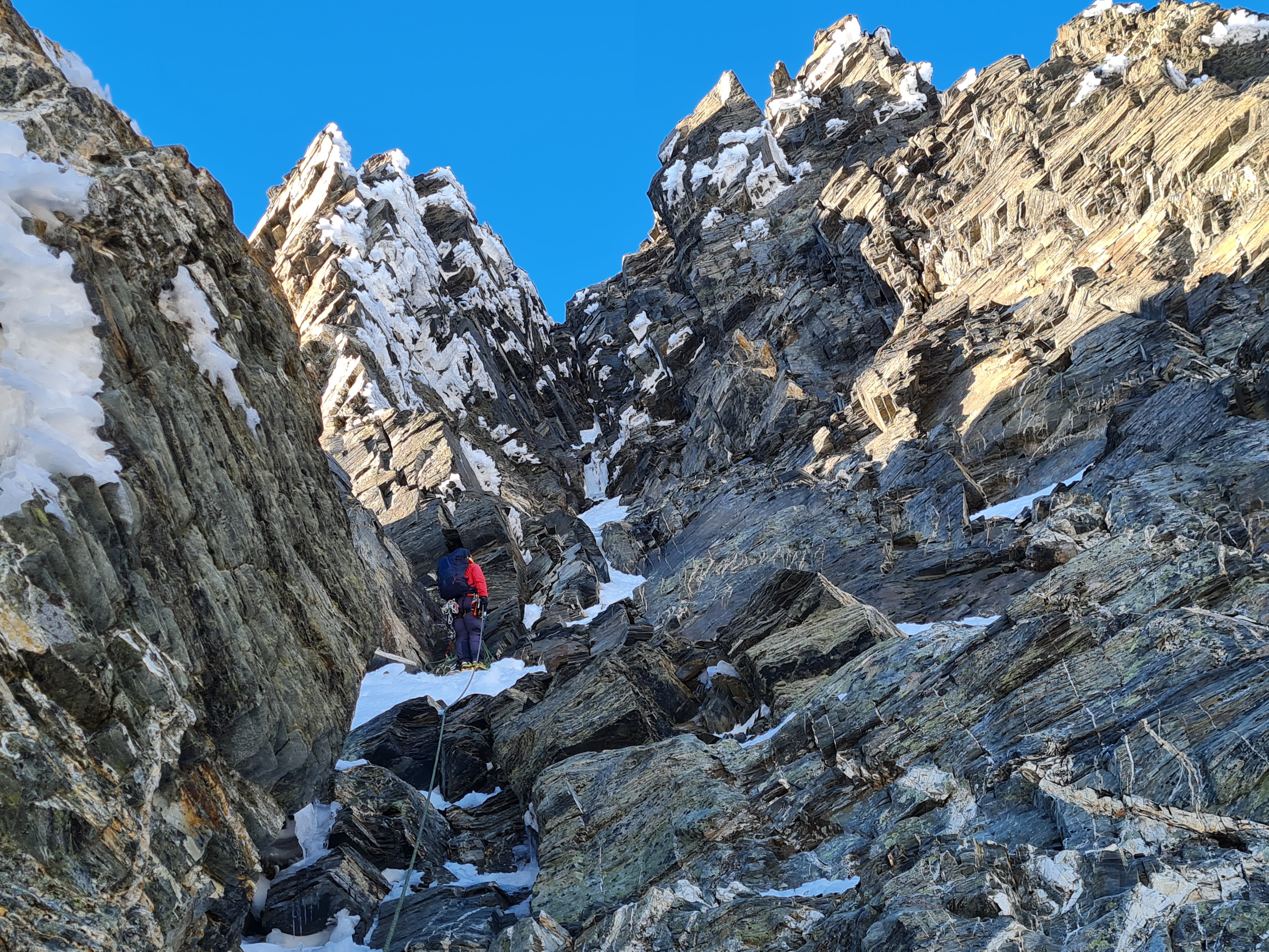 Topping out of the rock corner. Above the climber is the final pitch (gully to chimney) to the ridge