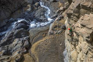 Climber climbs route with river below