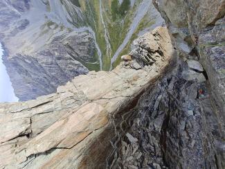 Illustrating the precarious nature of the approach gully (approach from above, left of frame), and the rock feature the route follows (pillar/corner by rope). 'Actions Speak Louder' arete in background